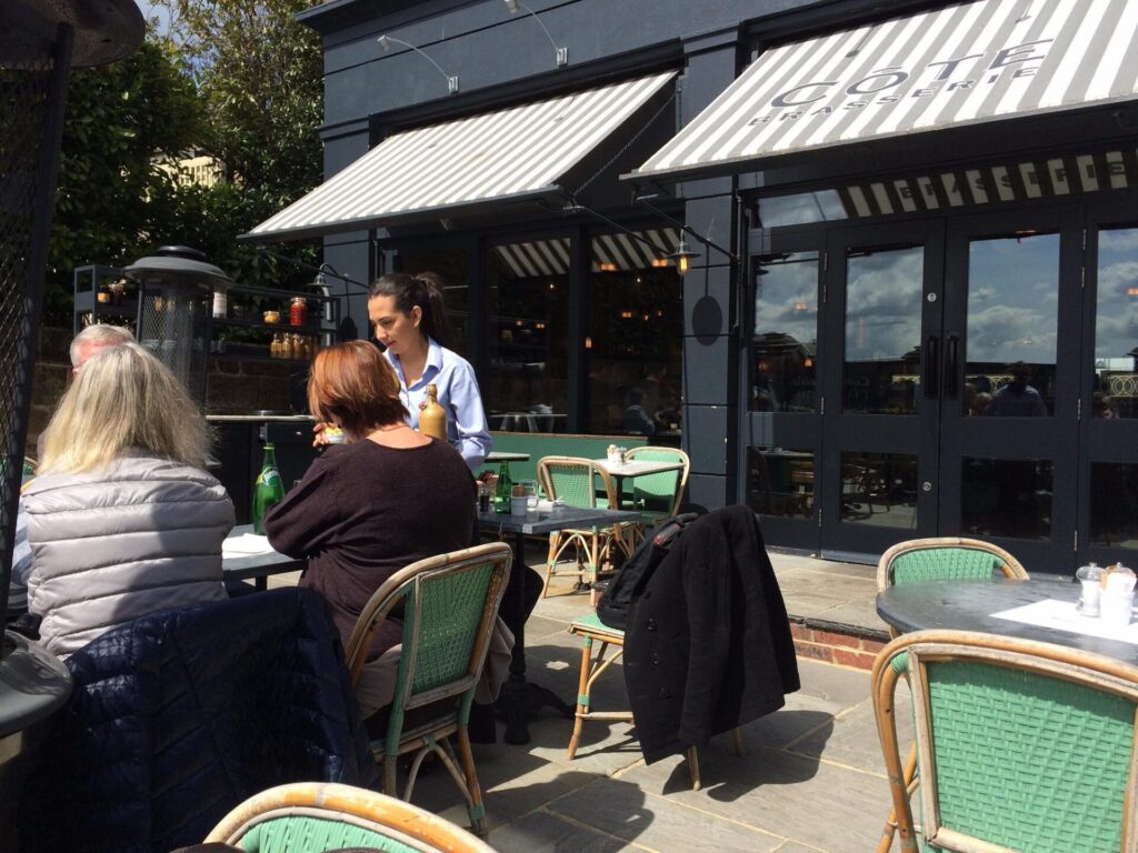 Three people at an outside table being served.