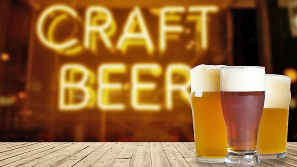 AThree full glasses of craft beer with an illuminated sign behind saying "Craft Beers"
