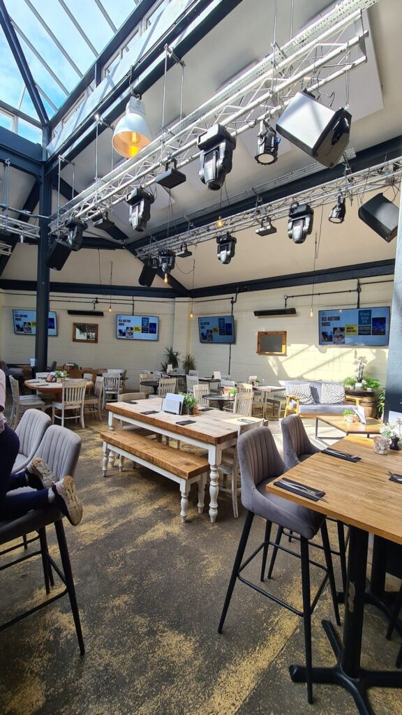 Empty, modern restaurant interior with wooden tables and varied seating.