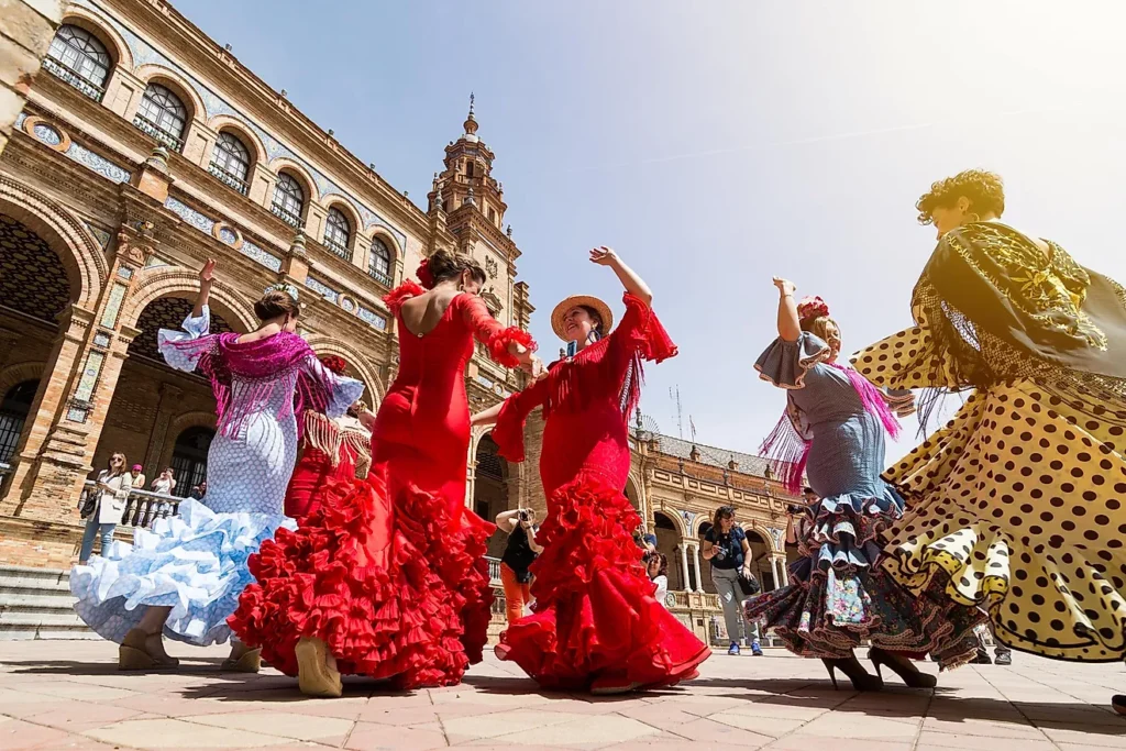 View from ground level upwards to a group of women flamenco dancers, dancing in a plaza.