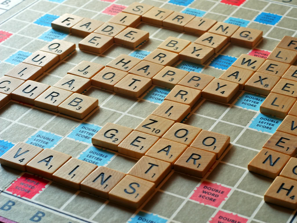 Square letter tiles on a scrabble board spelling various words. Board has a few different coloured squares for letter value multipliers.