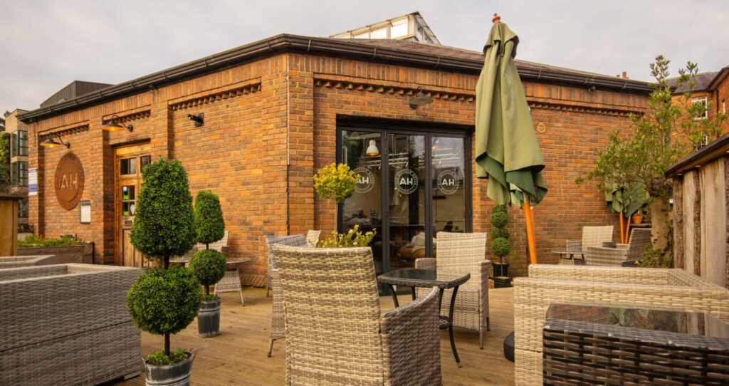 Redbrick single storey building with glass doors and outside seating - coffee house